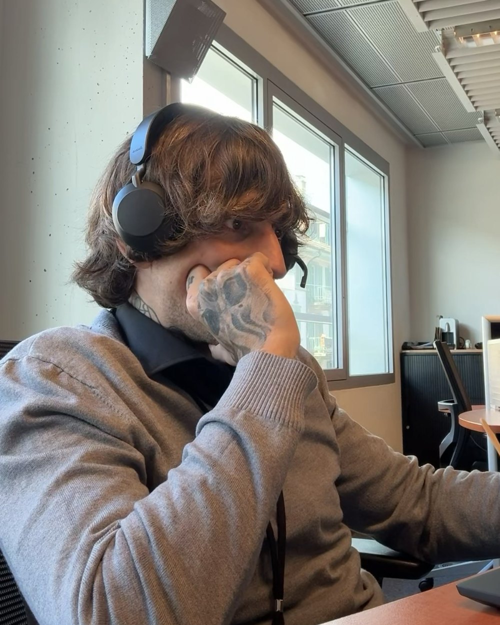 Gio Georgiou at his desk with a headset on, mid-call in a Swiss office