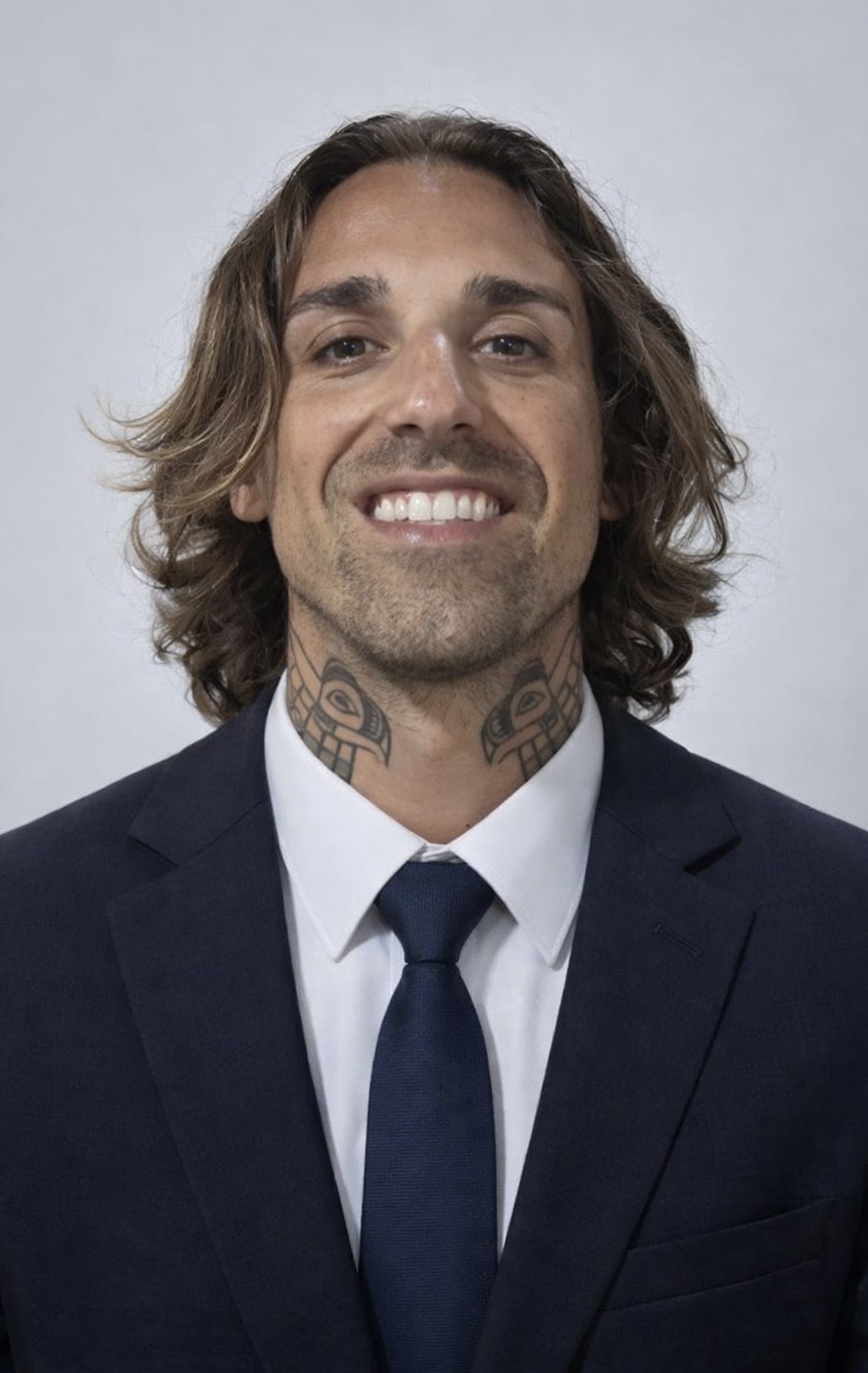 Gio Georgiou, smiling portrait in a navy suit and tie